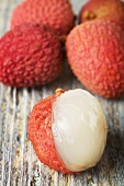 Lychees on wooden background, one partly peeled