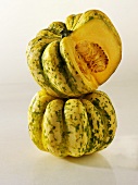 One whole acorn squash & one with a piece cut out, in a pile