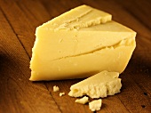 A piece of Cheddar cheese on a wooden background