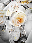 Schmutzige Teller, Gläser und Besteck im Spülwasser