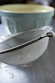 A sieve with a baking bowl in the background