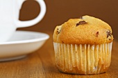 A chocolate chip muffin with a cup and saucer