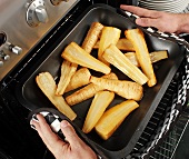Man taking roasted, halved parsnips out of the oven