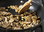 Sweating mushrooms and pine nuts in a frying pan