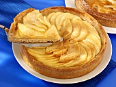 An apple tart with a piece cut on a cake plate