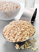 Rolled oats on a spoon and in a glass bowl