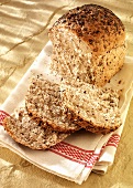 Wholemeal bread, partly sliced, on a tea towel