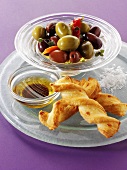 Marinated olives in a small glass dish with cheese straws
