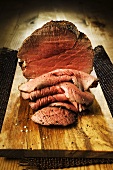Roast beef, slices carved, on chopping board