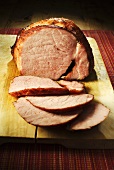 Roast ham, slices carved, on chopping board