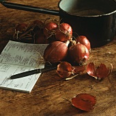 Red onions, a note book, a knife and a saucepan