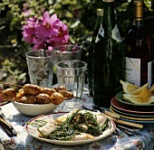 Salmon with glasswort and minced meat kebabs on table in the garden