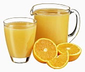 Orange juice in jug and glass with fresh oranges