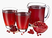 Pomegranate juice in jug & two glasses, fresh pomegranate