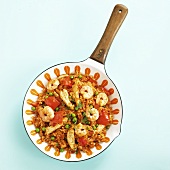 Paella with chicken and prawns in frying pan from above