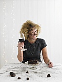 Woman with red wine sitting in front of exploded Christmas pudding