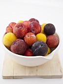 Different types of plums in a bowl