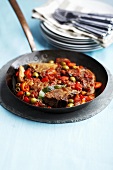 Lamb chops with tomatoes and olives in frying pan
