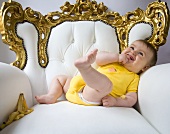Baby in an ornate armchair with banana skin