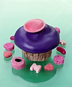 Muffin mit lila Zuckerguss und Brause-Ufo und Süssigkeiten