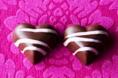 Two chocolate hearts on purple background