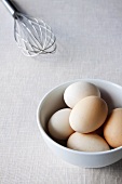 Fresh eggs with whisk in background