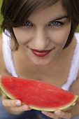 Young woman holding slice of watermelon