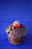 Chocolate muffin with strawberry against blue background