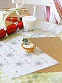 A mince pie and a glass of milk on a Christmassy table