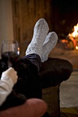 Woman with glass of red wine in front of fire