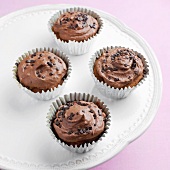 Four chocolate cupcakes on cake stand