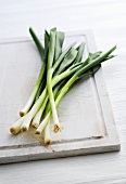 Several spring onions on chopping board