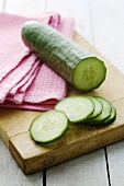 Cucumber, partly sliced, on chopping board
