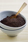 Brown mustard seeds in bowl with wooden spoon