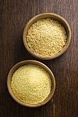Two different sorts of couscous in bowls on wooden background