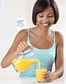 A woman pouring orange juice into a glass