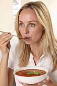 A woman eating tomato soup