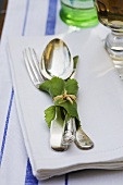 Cutlery wrapped in a vine leaf on a serviette