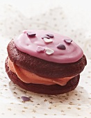 A whoopie pie with pink icing and sugar hearts