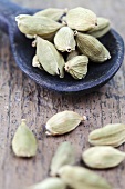 Dried cardamom pods with a wooden spoon