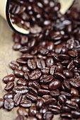 Geröstete Kaffeebohnen vor umgekipptem Becher