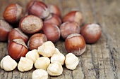 Whole hazelnuts and shelled hazelnuts on a wooden surface
