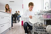 Boy emptying dishwasher