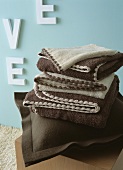 Brown felt cushion and brown and beige blankets in front of blue wall with white letters