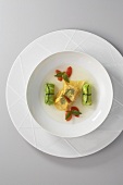 Light tomato essence with pointed cabbage roulade and salmon ravioli