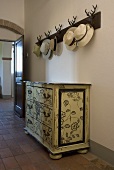 Chest of drawers painted with flowers cloakroom with hats in a entrance to a country home