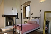 Iron bedstead with white pink bed linen in a Mediterranean country home