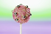 A cake pop, chilled and decorated with light chocolate and sugar strands