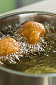 Yeast doughnuts being fried in oil