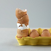 A stack of egg shells and fresh eggs in an egg box